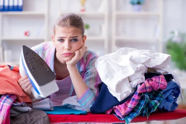 Üzücü kadın evde kıyafetleri ütülüyor.