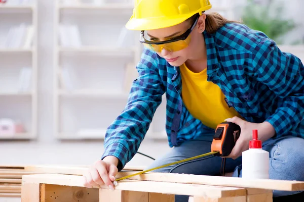 Tamirci kadın marangoz ahşap döşemeleri kesiyor.