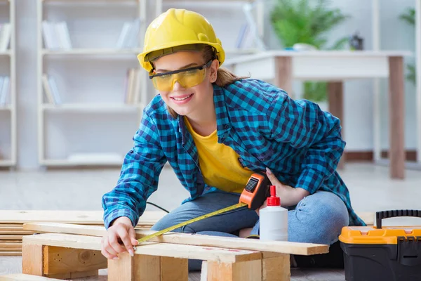 Tamirci kadın marangoz ahşap döşemeleri kesiyor.