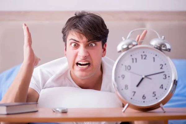 Hombre en la cama frustrado sufriendo de insomnio con un zueco de alarma — Foto de Stock