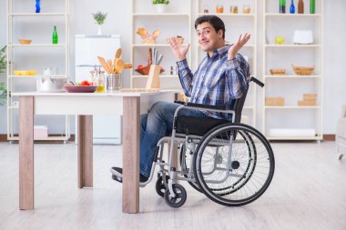 Engelli genç koca mutfakta çalışıyor.