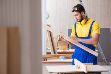 Genç tamirci marangoz odun kesiyor.