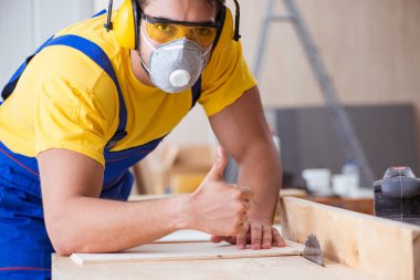 Genç bir marangoz dairesel testereyle odun kesiyor.