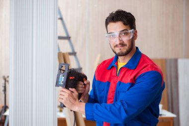 Elektrikli testereyle çalışan genç bir tamirci.