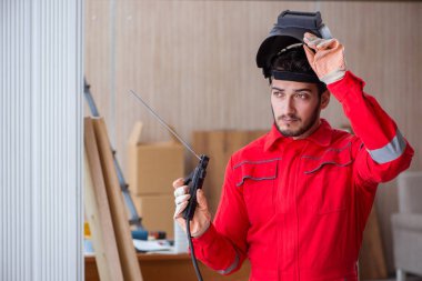 Kaynak tabancası elektrot ve kask takan genç bir tamirci.