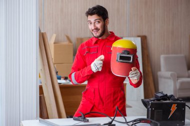 Kaynak tabancası elektrot ve kask takan genç bir tamirci.