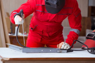 Kaynak tabancası elektrot ve kask takan genç bir tamirci.