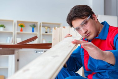 Genç marangoz ahşap kalaslarla çalışıyor.