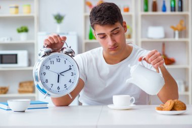 Çalar saati olan bir adam kahvaltıda uyuyakalıyor.