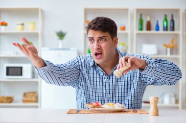 Genç koca öğle yemeğinde tatsız yemekler yiyor.