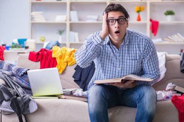 Genç adam dağınık bir odada çalışıyor.