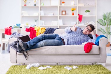 Genç adam dağınık bir odada çalışıyor.