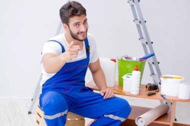 Tamirci, duvar kağıdıyla evde tadilat yapıyor.