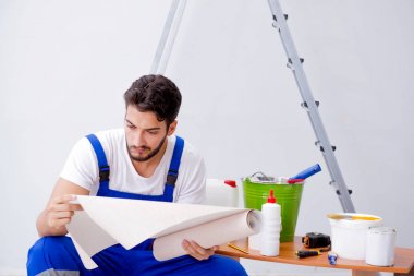 Tamirci, duvar kağıdıyla evde tadilat yapıyor.