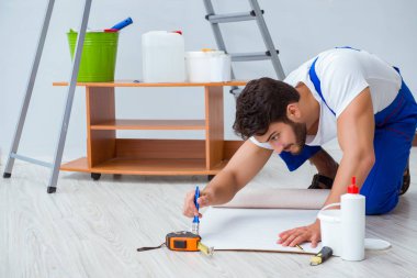 Tamirci, duvar kağıdıyla evde tadilat yapıyor.