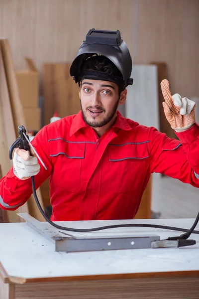 Young repairman with a welding gun electrode and a helmet weldin — Stock Photo, Image