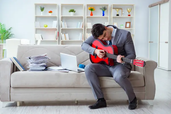 Evde gitar çalan bir iş adamı.