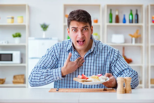 Молодой муж ест безвкусную еду дома на обед — стоковое фото