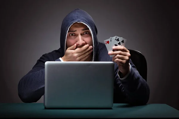 Joven con una sudadera con capucha sentado frente a una computadora portátil — Foto de Stock