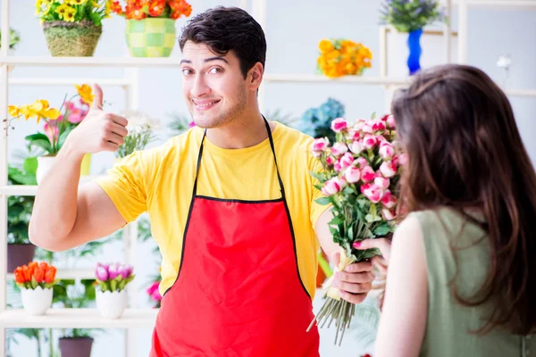 Çiçekçi dükkanında çiçek satıyor.