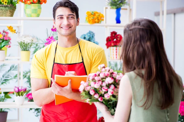 Çiçekçi dükkanında çiçek satıyor.