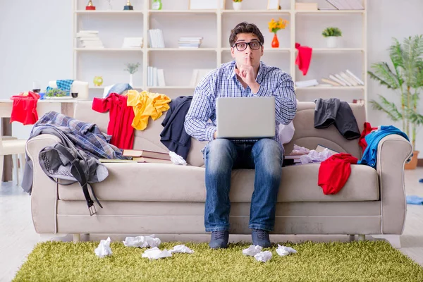 Genç adam dağınık bir odada çalışıyor.