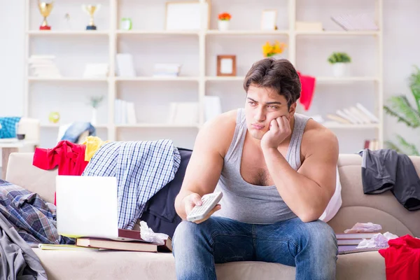 Genç adam dağınık bir odada çalışıyor.