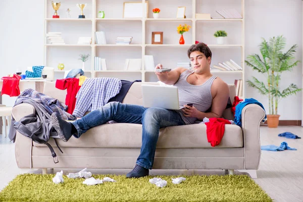 Genç adam dağınık bir odada çalışıyor.