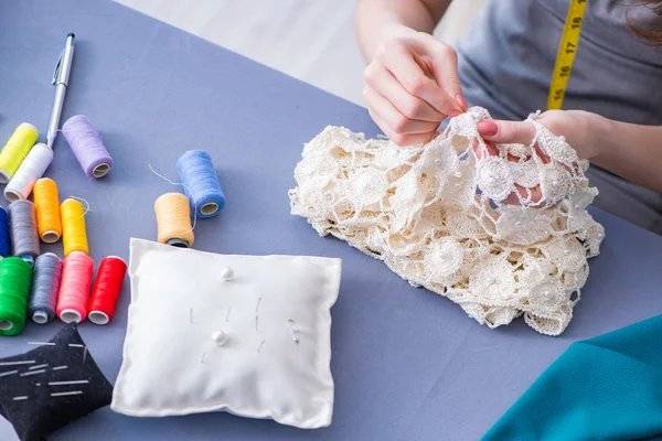 Kadın terzi dikiş dikmek için dikiş dikiyor.