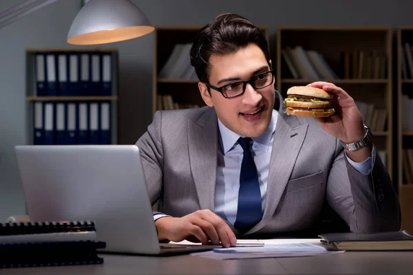 ビジネスマンは夜遅くハンバーガーを食べて — ストック写真