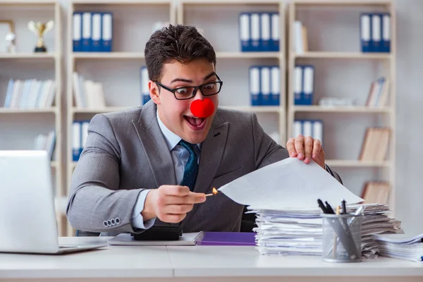 Palyaço işadamı ofiste kağıt yakıyor.