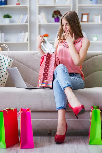 Jovem com sacos de compras em casa no sofá — Fotografia de Stock