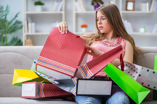 Jovem com sacos de compras em casa no sofá — Fotografia de Stock