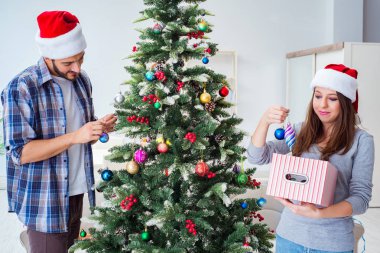 Genç aile Noel ağacını mutlu bir vesileyle süslüyor.