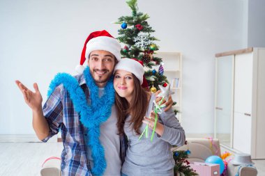 Genç aile Noel ağacını mutlu bir vesileyle süslüyor.