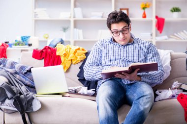 Genç adam dağınık bir odada çalışıyor.