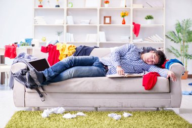 Genç adam dağınık bir odada çalışıyor.