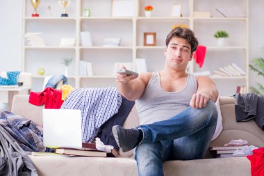 Genç adam dağınık bir odada çalışıyor.