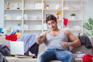 Genç adam dağınık bir odada çalışıyor.