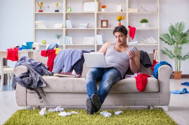 Genç adam dağınık bir odada çalışıyor.