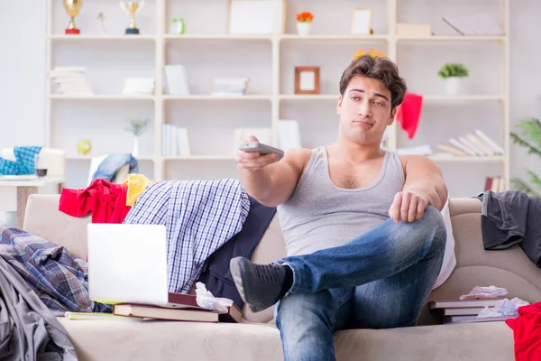 Genç adam dağınık bir odada çalışıyor.