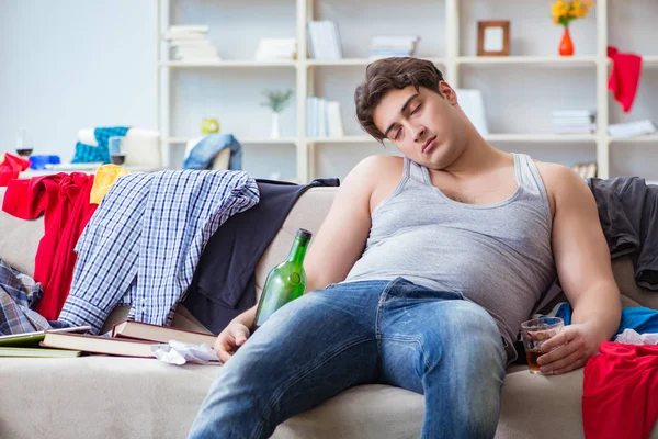 Jongeman student dronken alcohol drinken in een rommelige kamer — Stockfoto