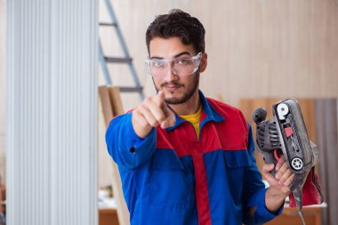 Elektrikli testereyle çalışan genç bir tamirci.