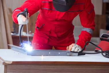 Kaynak tabancası elektrot ve kask takan genç bir tamirci.