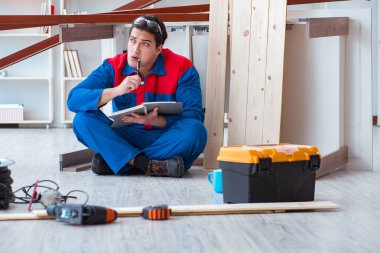 İnşaatta defter planlama yapan genç bir marangoz.