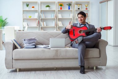 Evde gitar çalan bir iş adamı.