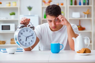 Çalar saati olan bir adam kahvaltıda uyuyakalıyor.
