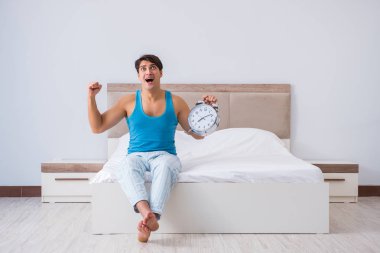 Genç adam yatakta uyanıyor.