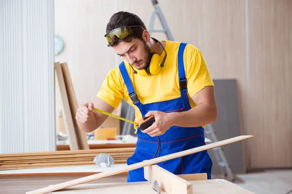 Genç bir marangoz dairesel testereyle odun kesiyor.