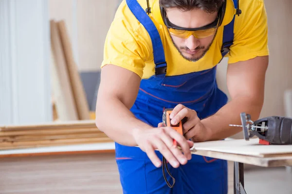 Ung reparatör snickare arbetar skärande trä på cirkulär såg — Stockfoto